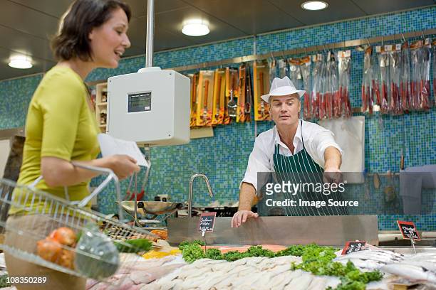 fishmonger talking to customer in supermarket - fishmonger stock pictures, royalty-free photos & images