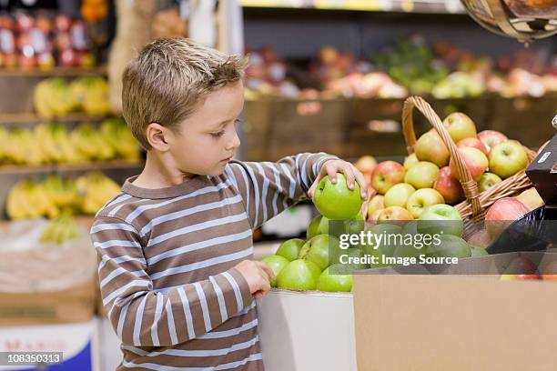 boy in supermarket holding an apple - only boys stock pictures, royalty-free photos & images