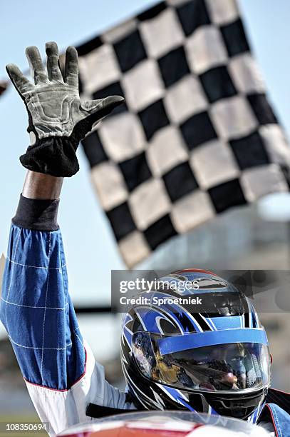 triumphant racing driver waves at crowd - checkered race flag stockfoto's en -beelden