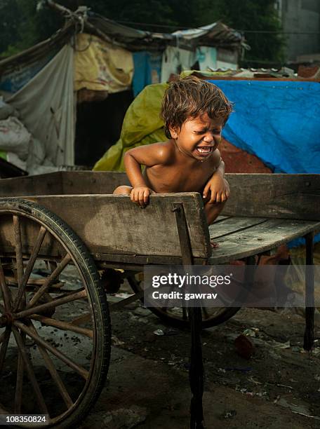 poor, hungry child sitting on a cart and crying loudly - childhood hunger stock pictures, royalty-free photos & images