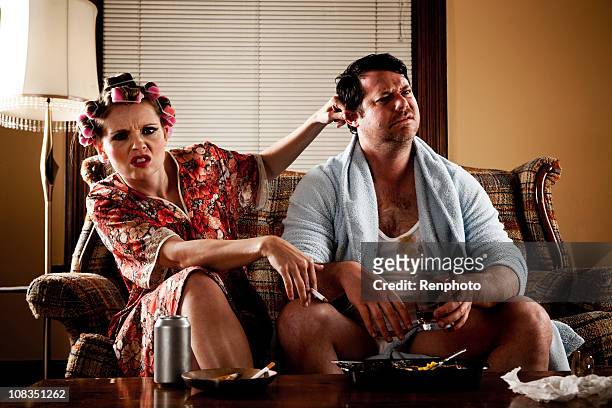 white trash series: couple sitting on their couch - ugly woman stockfoto's en -beelden