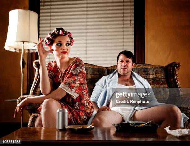 white trash series: couple sitting on their couch - ugly woman stockfoto's en -beelden