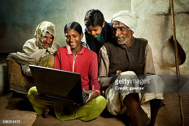 happy village girl using laptop with mother, brother and grandfa - rural scene stock pictures, royalty-free photos & images