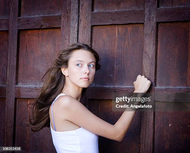 beautiful girl knocking on a door - knocking stockfoto's en -beelden