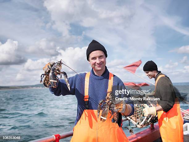 fishermen on boat holding lobsters - hummerkorb stock-fotos und bilder