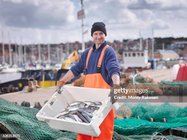 fisherman with box of fish in harbour - preparazione al parto foto e immagini stock