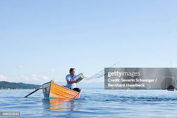 throwing buckets of water ot ouf boat - sinking stockfoto's en -beelden
