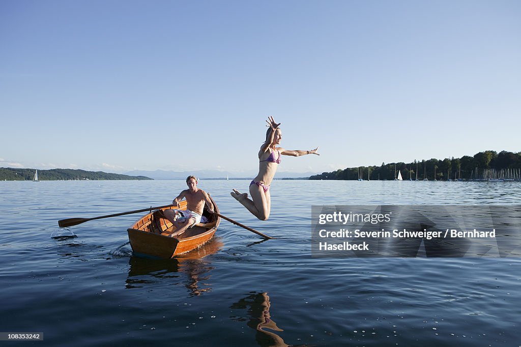 Young woman jumping off a row boat