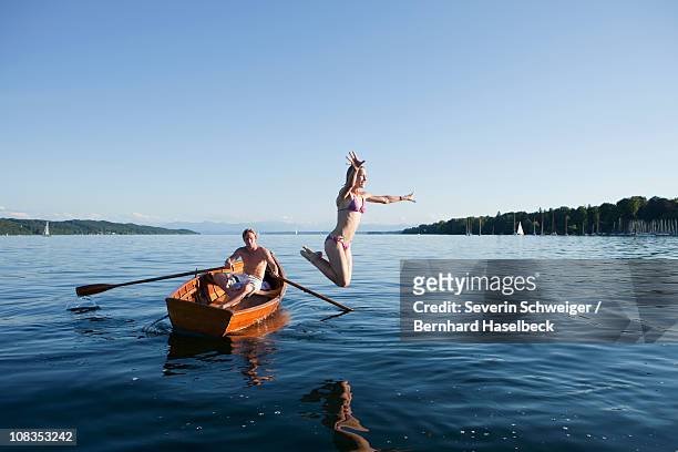 young woman jumping off a row boat - starnberger see stock pictures, royalty-free photos & images