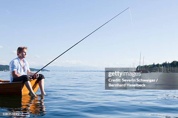 businessman with fishing rod in rowboat - angel brinks stock-fotos und bilder