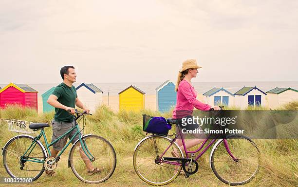 couple push bicycles over beach - summer press day ストックフォトと画像