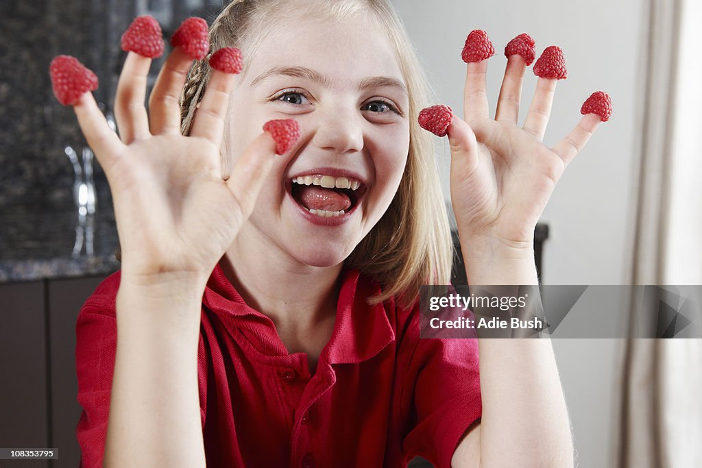 Girl with raspberries on fingers