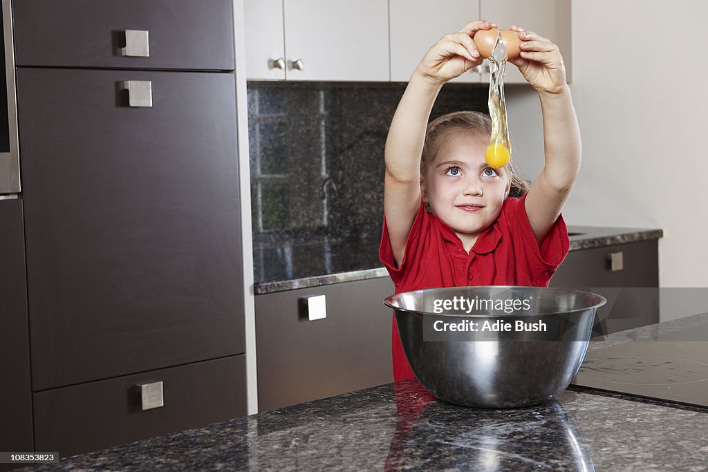 Girl cracking egg over bowl