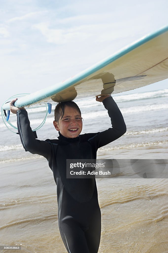 Young boy with surf board on his head