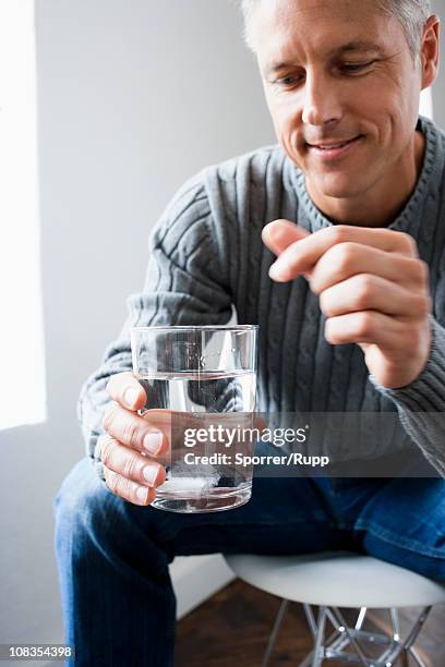 man dropping pill into glass of water - dissolving stock-fotos und bilder