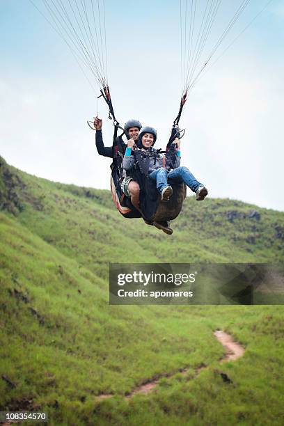 soaring - young couple doing tandem paragliding - paragliding stockfoto's en -beelden