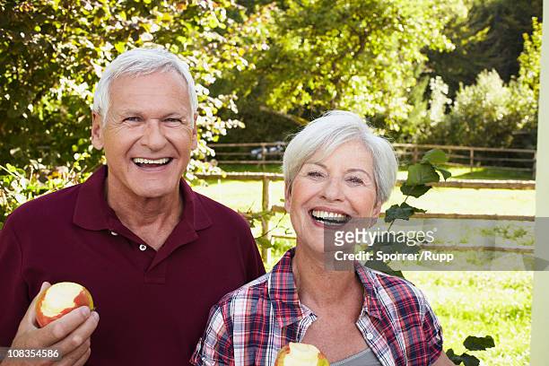 senior couple eating apples smiling - mature men foto e immagini stock