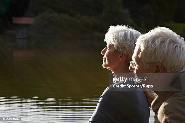 senior couple enjoying sunset - seeufer stock-fotos und bilder