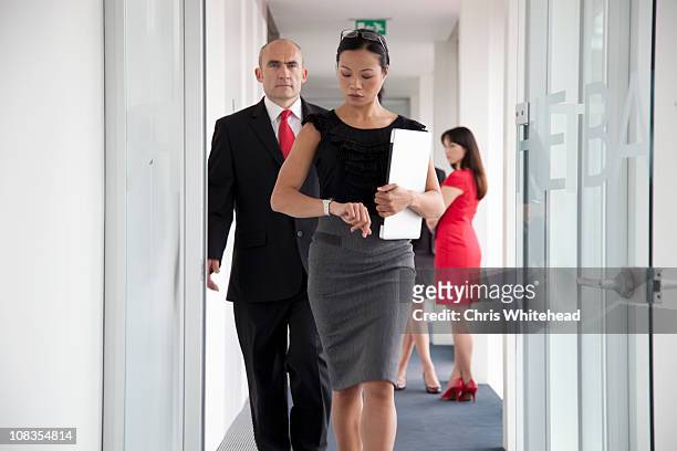 businesspeople walking down corridor - time management stock pictures, royalty-free photos & images