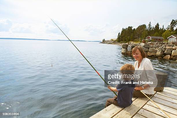 smiling grandmother watching fishing boy - beautiful swedish women stock pictures, royalty-free photos & images