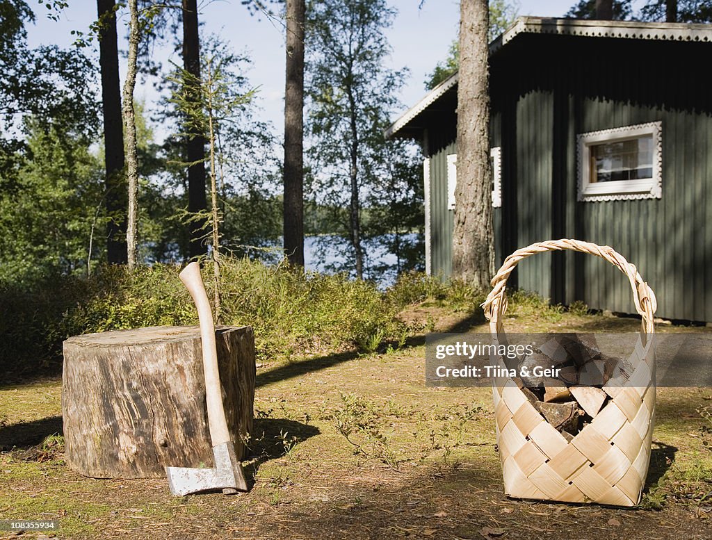Axe and firewood by wooden cabin