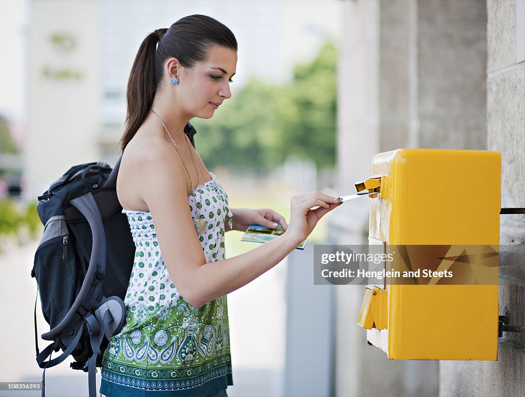 Young woman posting postcard