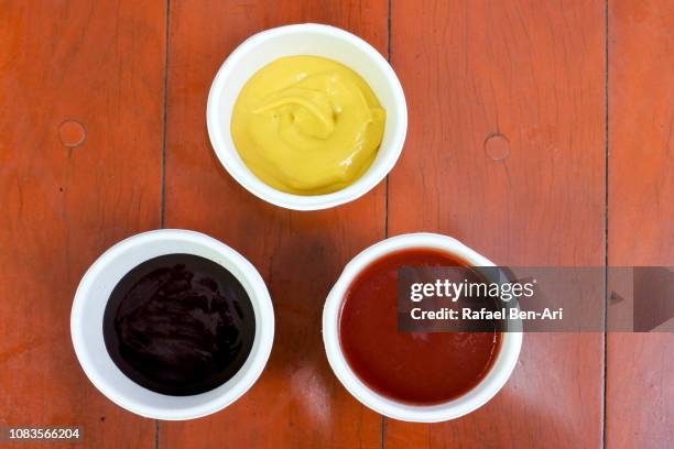 tomato sauce mustard and bbq sauce on a wooden table - salsa barbecue foto e immagini stock