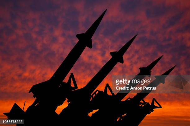 four rockets of anti-aircraft missile system are directed upwards against the background of sunset - russland stock-fotos und bilder