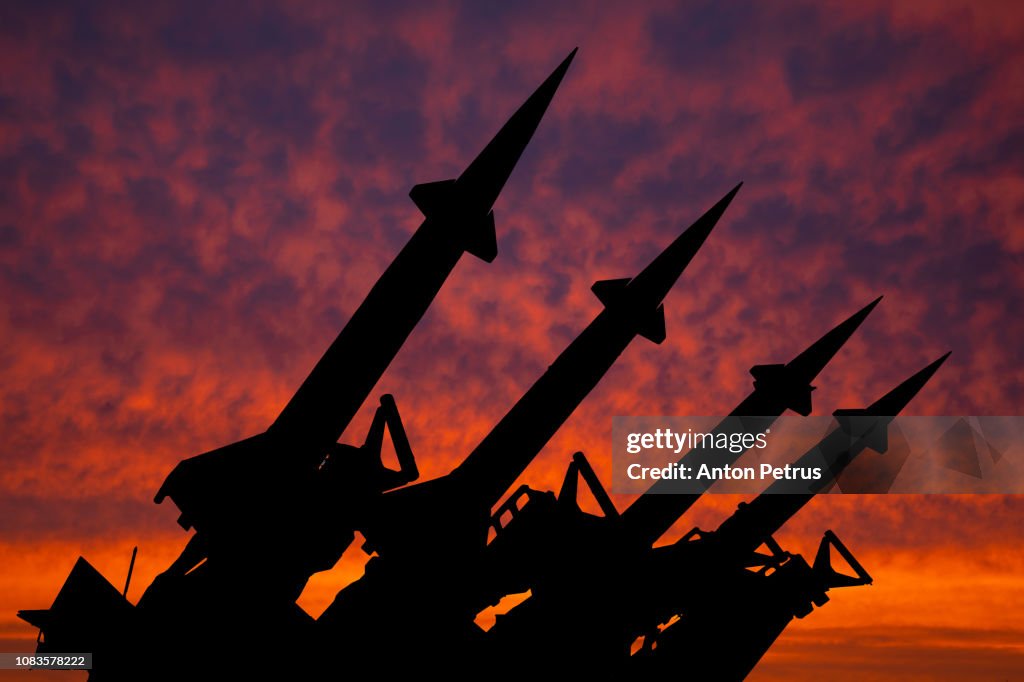 Four rockets of anti-aircraft missile system are directed upwards against the background of sunset