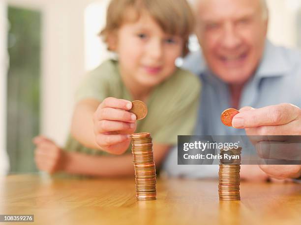 grandfather and grandson stacking coins - holding cash stock pictures, royalty-free photos & images