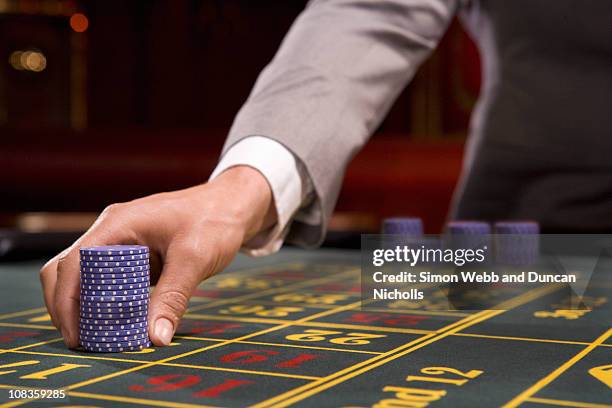 man placing bet with gambling chips - gagner casino photos et images de collection
