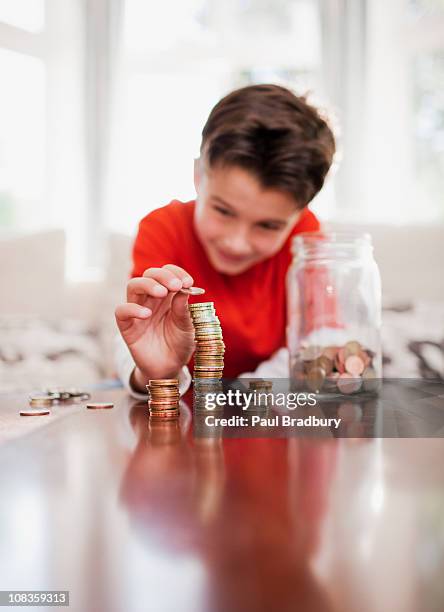 boy apilado de monedas - kids money fotografías e imágenes de stock