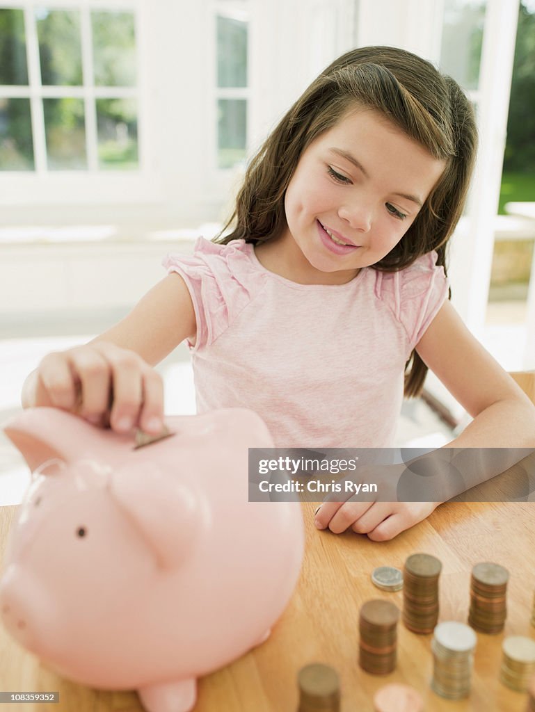 Girl putting coin into piggy bank