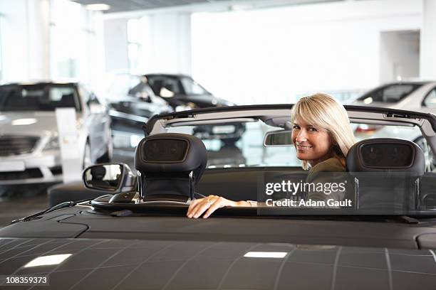 woman sitting in convertible in automobile showroom - reversing stock pictures, royalty-free photos & images