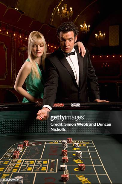 girlfriend watching boyfriend throwing dice at craps table - casino interior fotografías e imágenes de stock