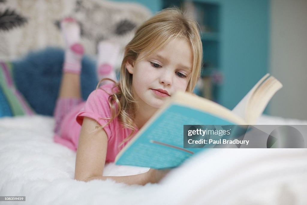 Girl laying on bed reading book