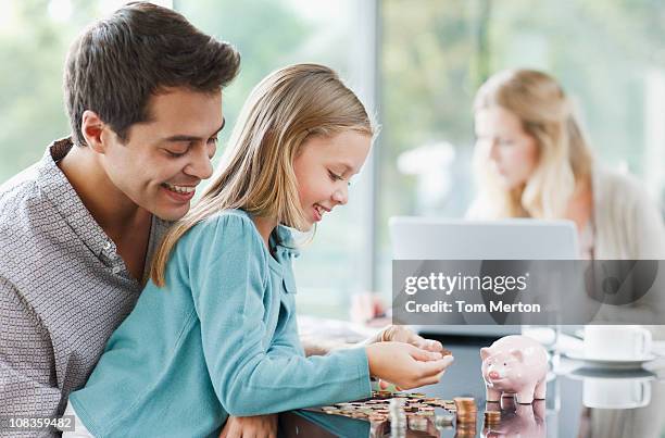 father watching daughter count coins - couple saving piggy bank stock pictures, royalty-free photos & images