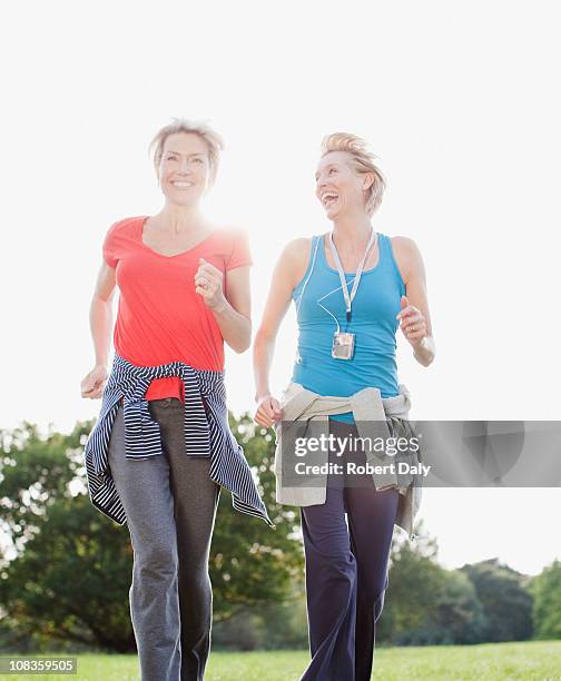 smiling women jogging together - alleen oudere vrouwen stockfoto's en -beelden