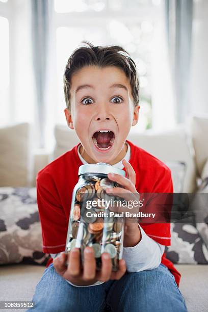 surprised boy holding jar full of coins - boys money stock pictures, royalty-free photos & images