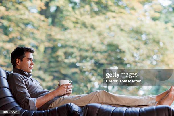 man reclining in chair drinking coffee - sun lounger 個照片及圖片檔