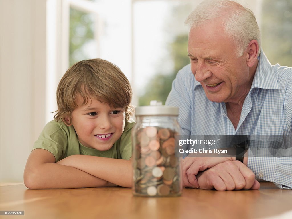Nonno e nipote guardano in Barattolo di vetro pieno di monete