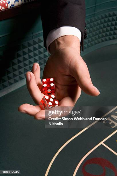 mans hand holding dice at craps table - craps table top stock pictures, royalty-free photos & images