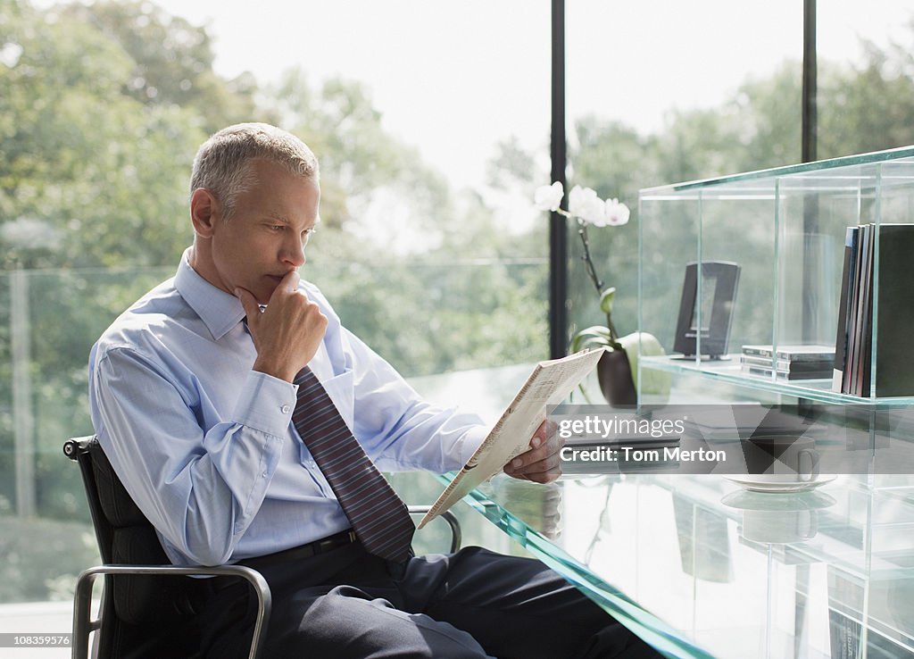 Businessman reading newspaper at desk