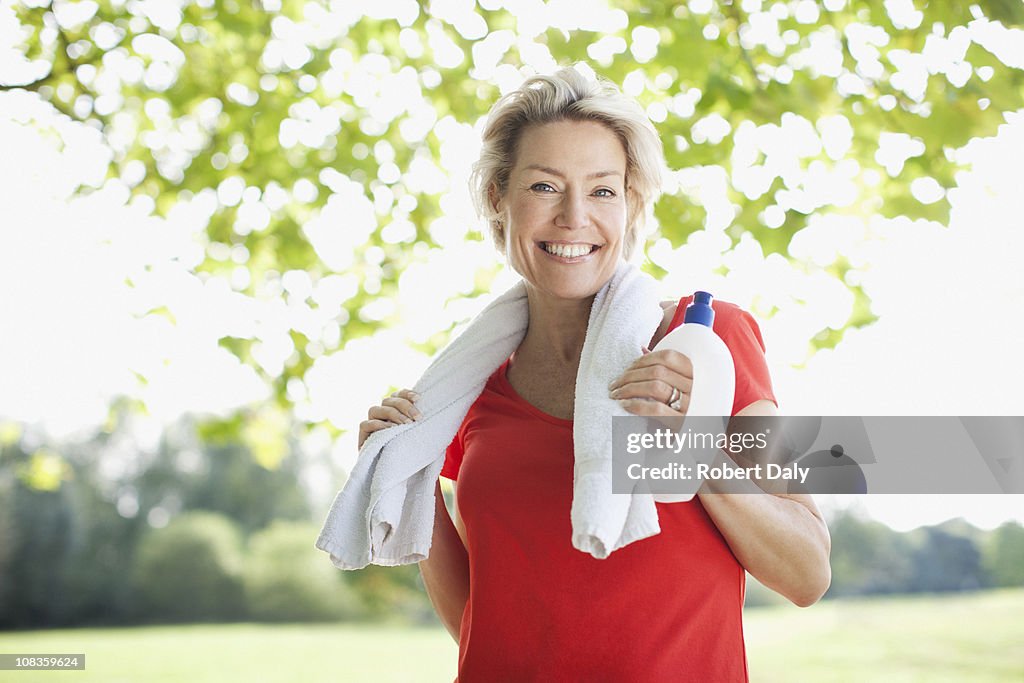 Lächelnde Frau mit Flasche Wasser und Handtuch
