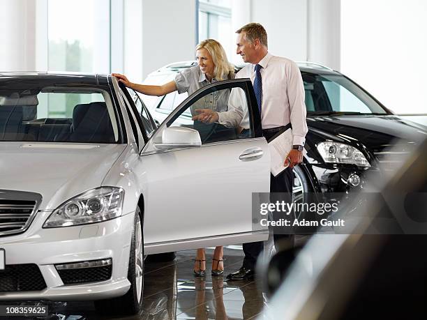 salesman talking to woman in automobile showroom - opel celebrates launch of new adam car stockfoto's en -beelden