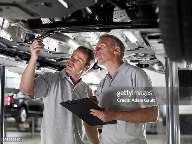 mechanics working underneath car - adam gault stock pictures, royalty-free photos & images