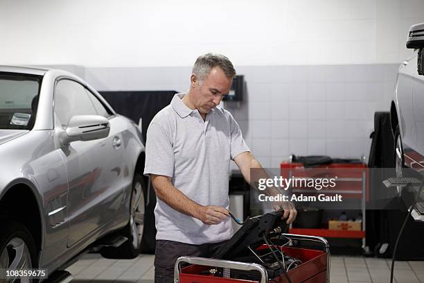 mechanic working on computer in auto repair shop - adam gault stock pictures, royalty-free photos & images