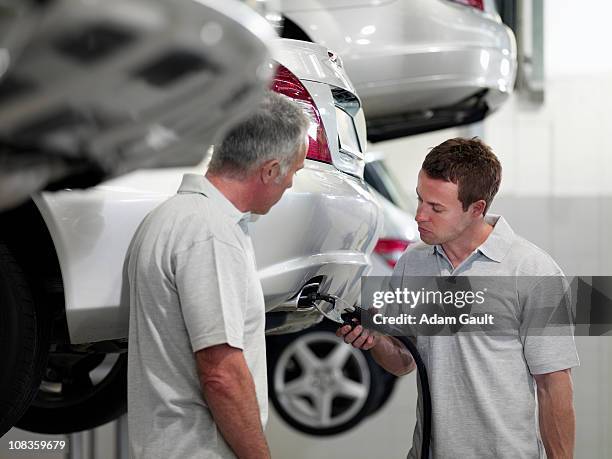 mechanics working on muffler in auto repair shop - adam gault stock pictures, royalty-free photos & images