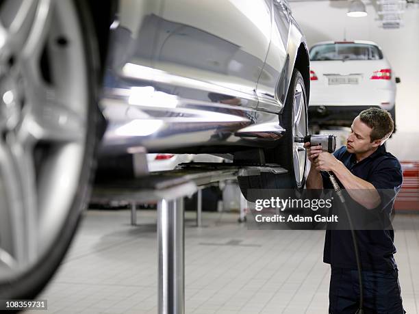 mechanic working on car in auto repair shop - reparaturwerkstatt stock-fotos und bilder
