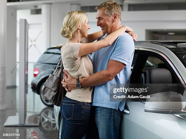 couple hugging in automobile showroom - adam gault stock pictures, royalty-free photos & images